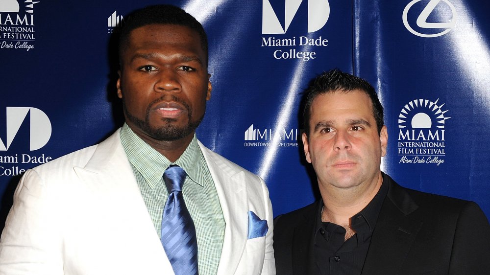 50 Cent in a white suit and blue tie, Randall Emmett in a black suit