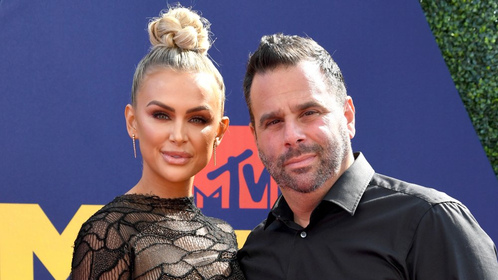 Lala Kent in a black dress with her hair in a high bun, Randall Emmett in a black button-up