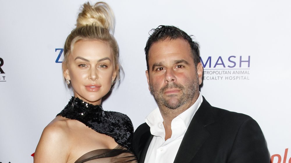 Lala Kent in a sheer dress and black shall, Randall Emmett in an open-collar black suit