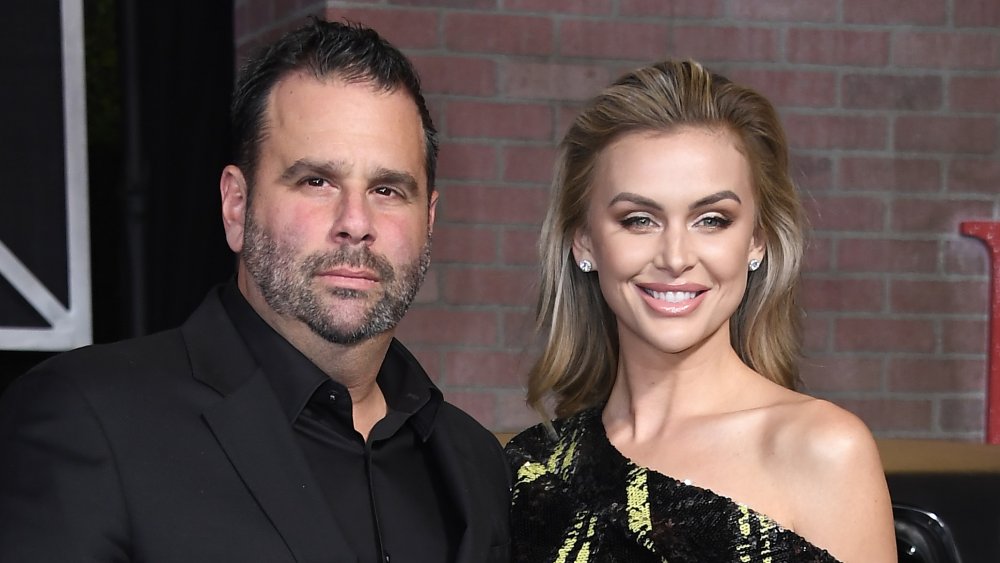 Randall Emmett in a black suit, Lala Kent smiling in a black-and-yellow dress