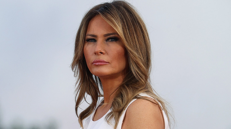 Melania Trump wearing pink lipstick looking solemn