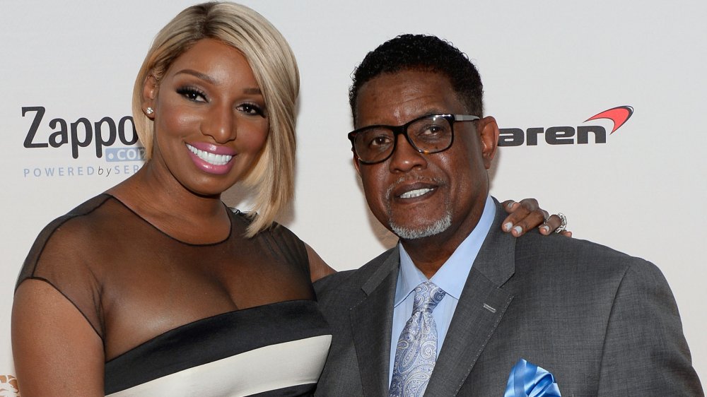 NeNe Leakes in a white-and-black dress, Gregg Leakes in a gray suit and blue shirt