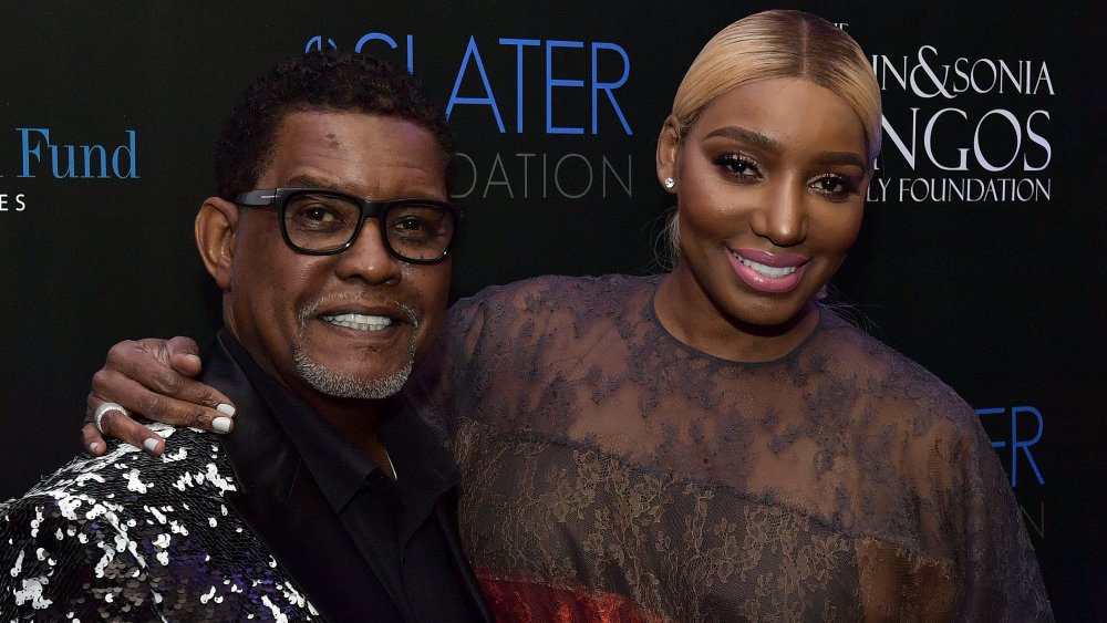 Gregg Leakes in a black-and-white suit, NeNe Leakes in a black-and-red lace dress
