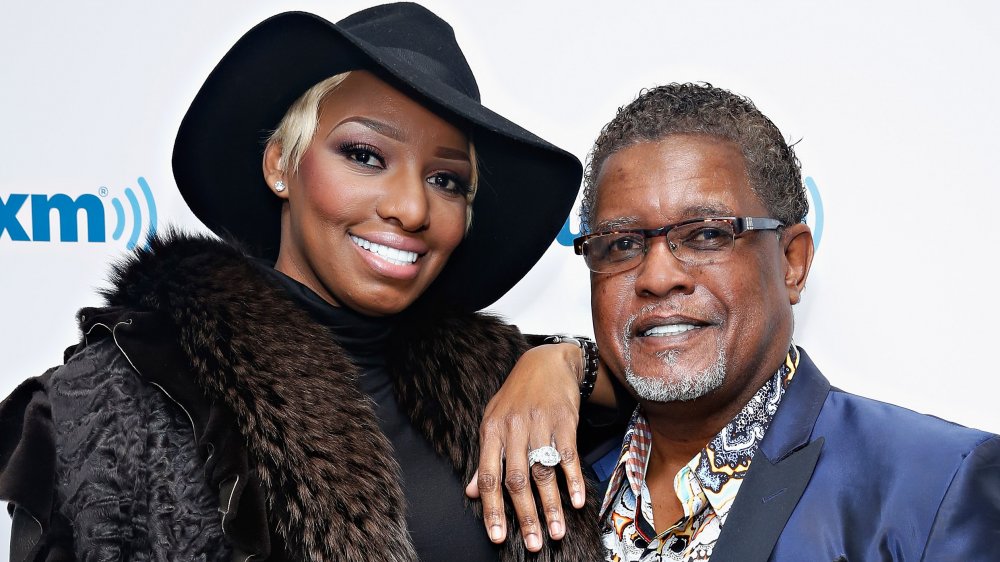 NeNe Leaks in a black coat and hat, Gregg Leakes in a shiny blue jacket and patterned shirt