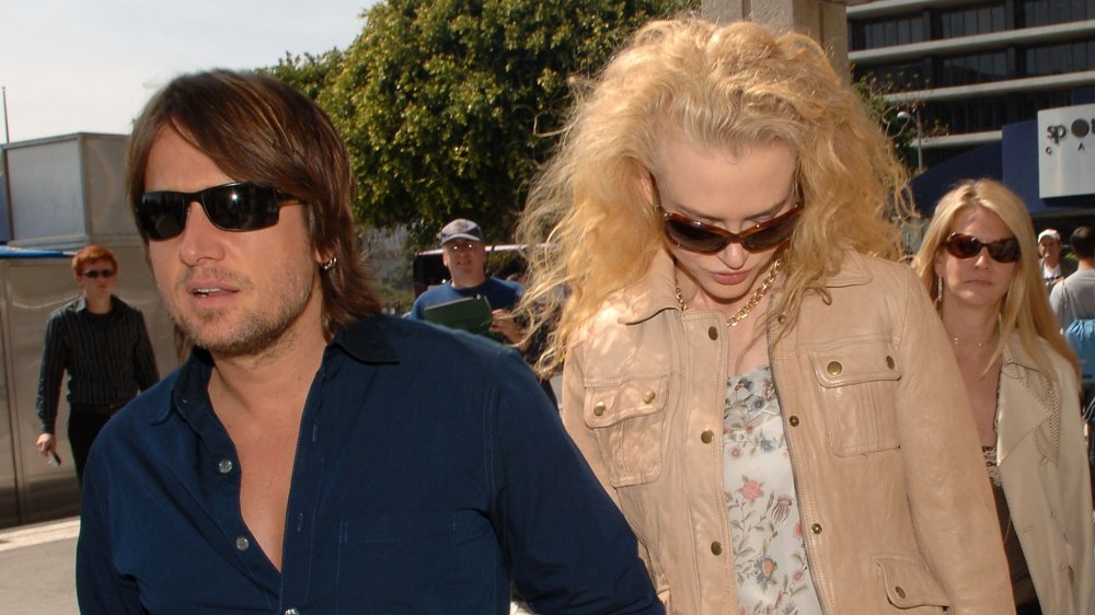 Keith Urban looking serious, Nicole Kidman looking down, both wearing sunglasses