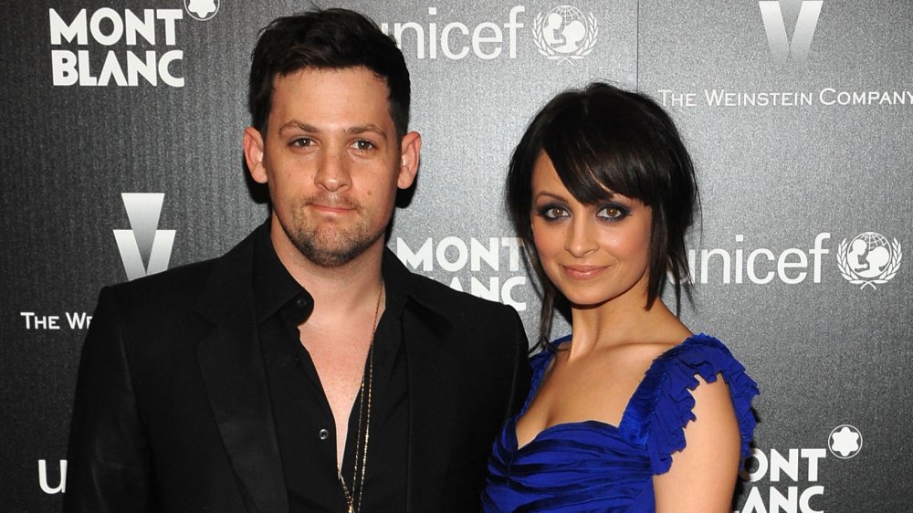 Joel Madden in a black blazer and open button-up shirt, Nicole Richie in a blue dress