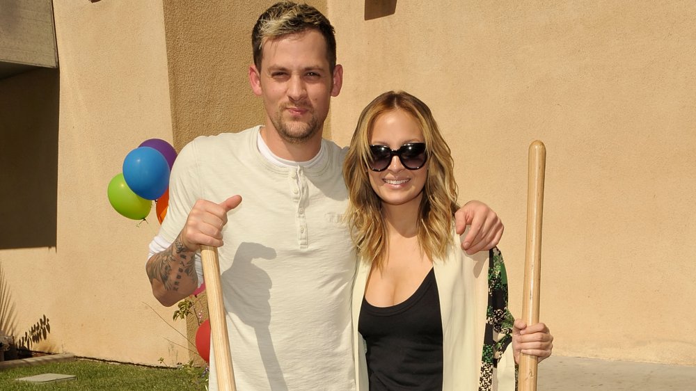 Joel Madden, Nicole Richie holding shovels and smiling outside