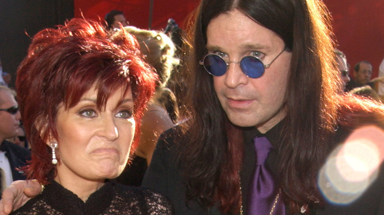 Sharon Osbourne frowning with Ozzy Osbourne on red carpet