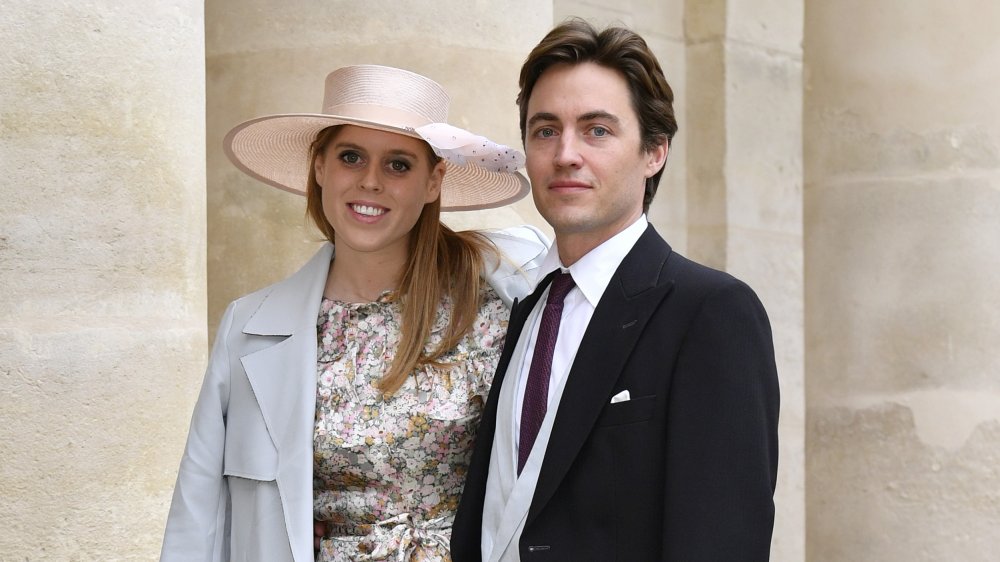 Princess Beatrice in a floral dress, posing with Edoardo Mapelli Mozzi, in a black suit with purple tie