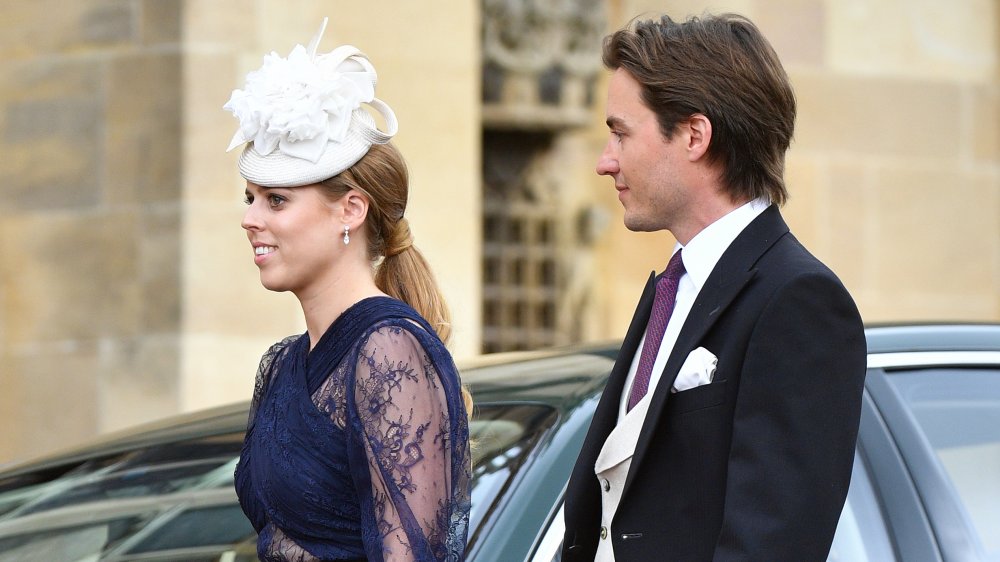 Princess Beatrice in a blue dress and white hat, walking as Edoardo Mapelli Mozzi looks on