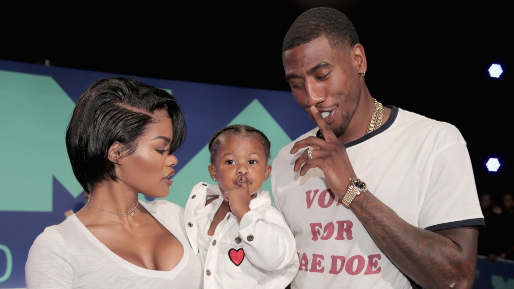 Teyana Taylor holding Iman Jr. alongside Iman Shumpert 