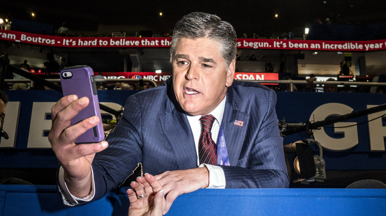 Sean Hannity holds a phone