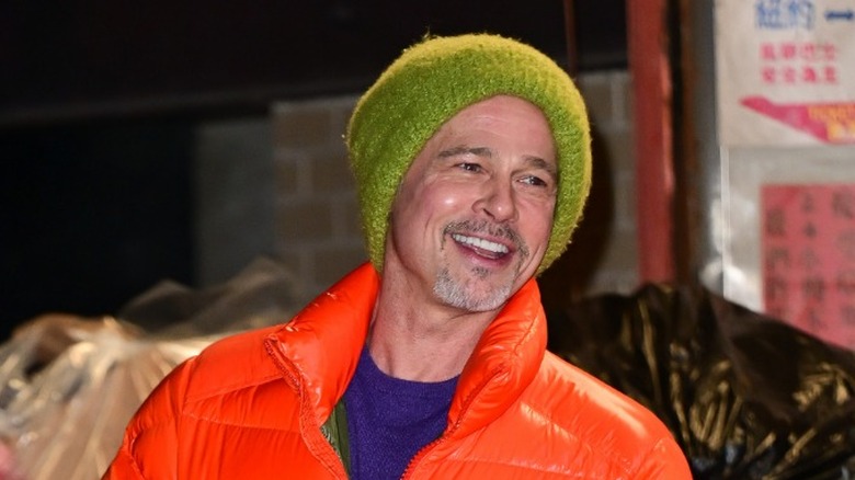 Brad Pitt wearing green hat orange jacket