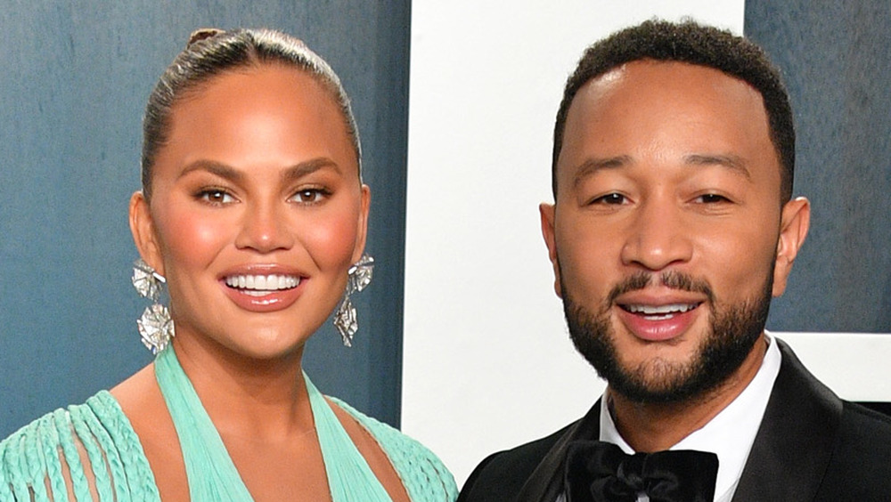 Chrissy Teigen and John Legend smiling adjacent to each other 