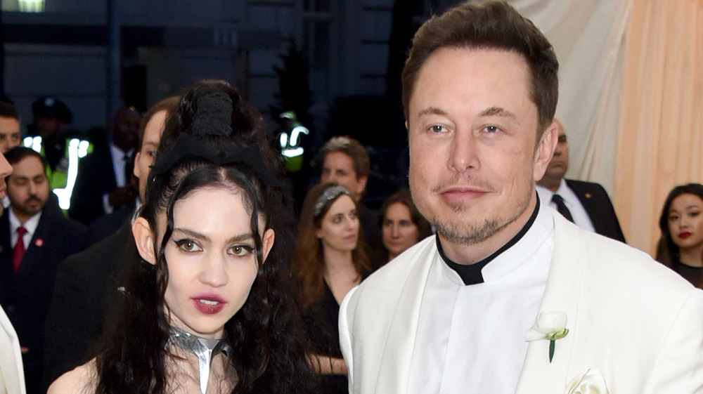 Grimes and Elon Musk, in a white tuxedo, pose for cameras together