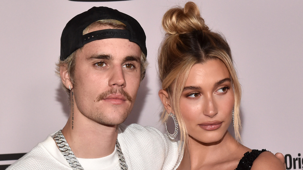 Justin Bieber and Hailey Baldwin pose for cameras together with Bieber looking upward and Baldwin looking to her left