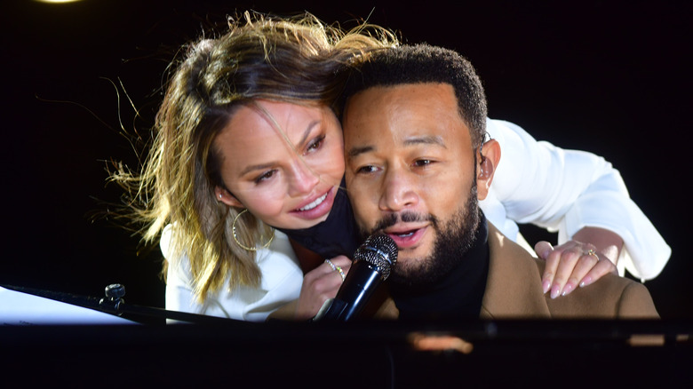 Chrissy Teigen over John Legend's shoulder as her performs