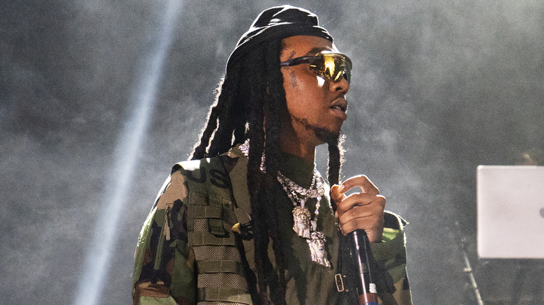 Takeoff, wearing a black beanie over dreads, performing