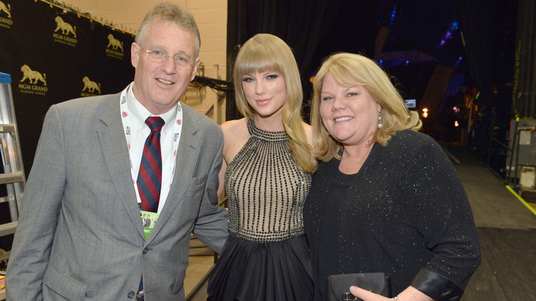 Scott, Taylor, and Andrea Swift smiling together backstage