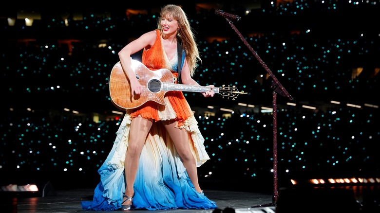 Taylor Swift playing guitar during Eras Tour concert in New Orleans