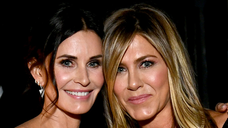 Courteney Cox and Jennifer Aniston smiling on red carpet