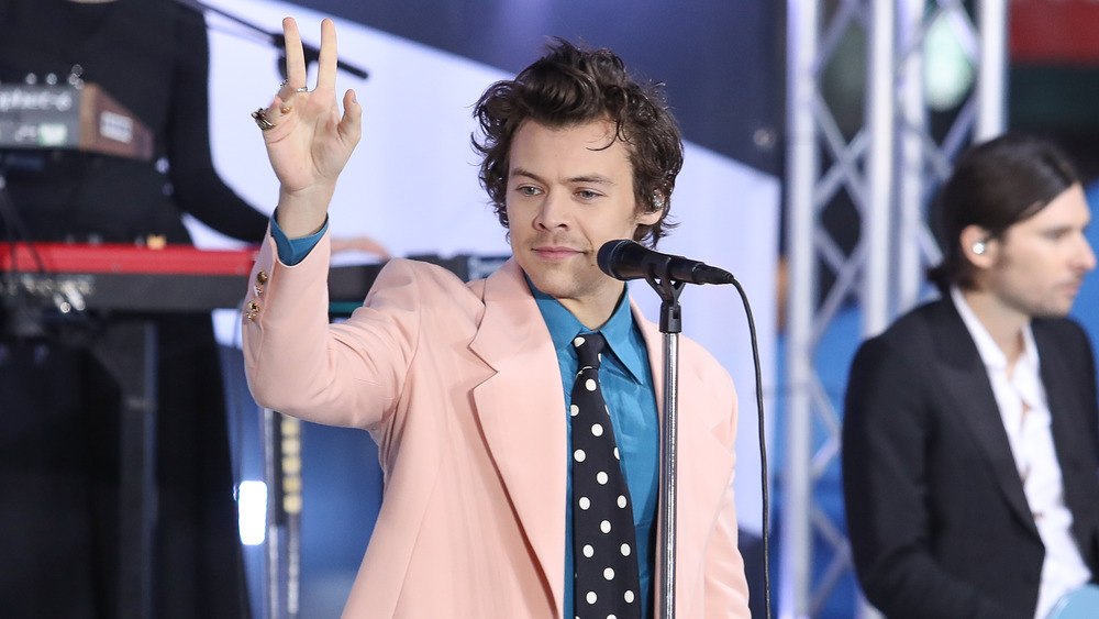 Harry Styles waves during a performance