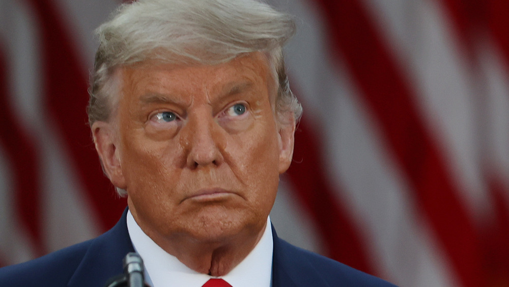 Donald Trump looks up at something while speaking on a podium