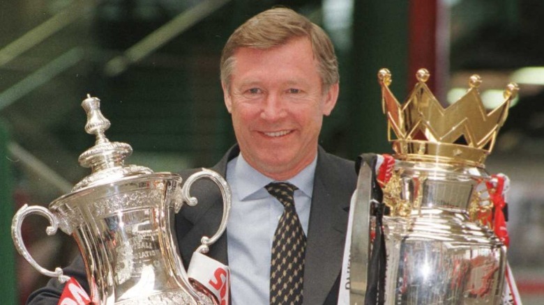 Alex Ferguson smiling with trophies