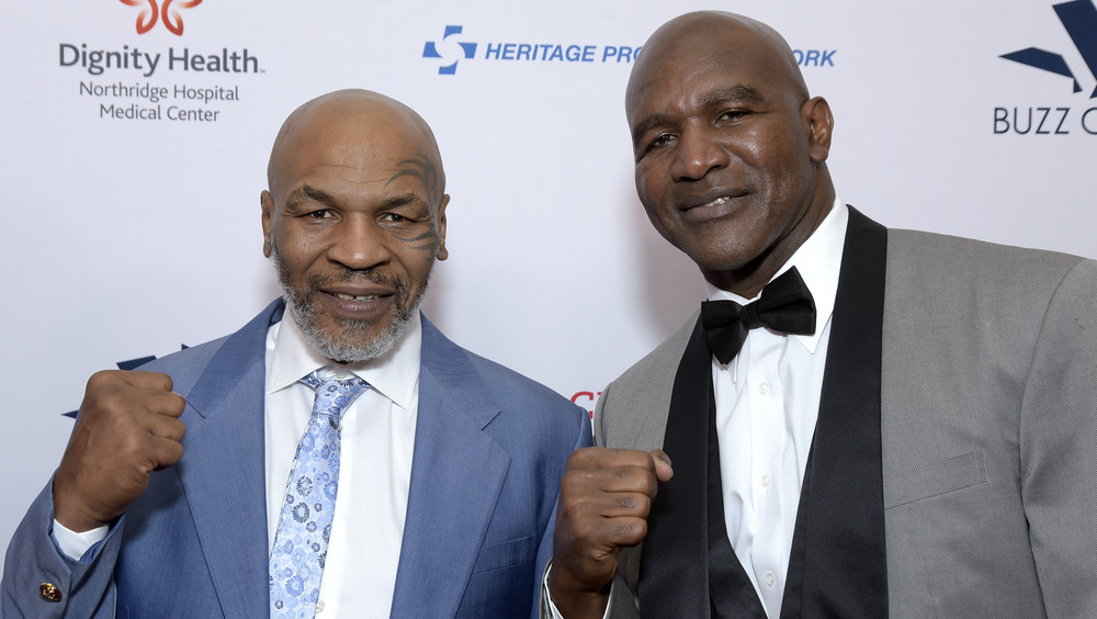 Mike Tyson and Evander Holyfield raising fists