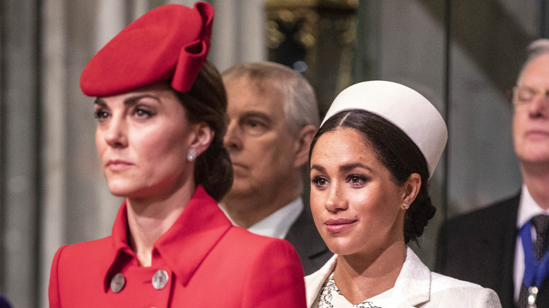 Kate Middleton standing in front of Meghan Markle