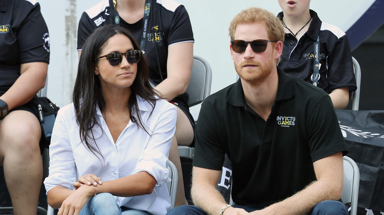 Meghan Markle Prince Harry seated and wearing sunglasses 