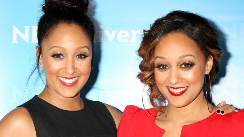 Tia Mowry and Tamera Mowry-Housley smiling for photographs together on red carpet