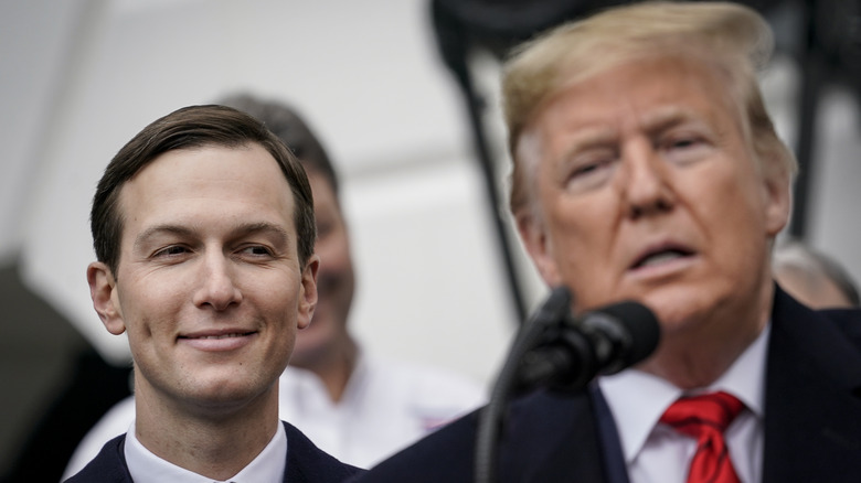 Jared Kushner smiling at Donald Trump