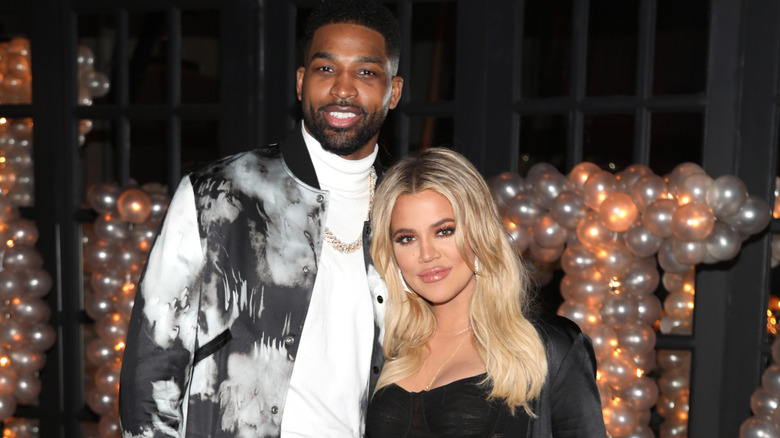 Khloe Kardashian posing with Tristan Thompson in front of balloons at an event