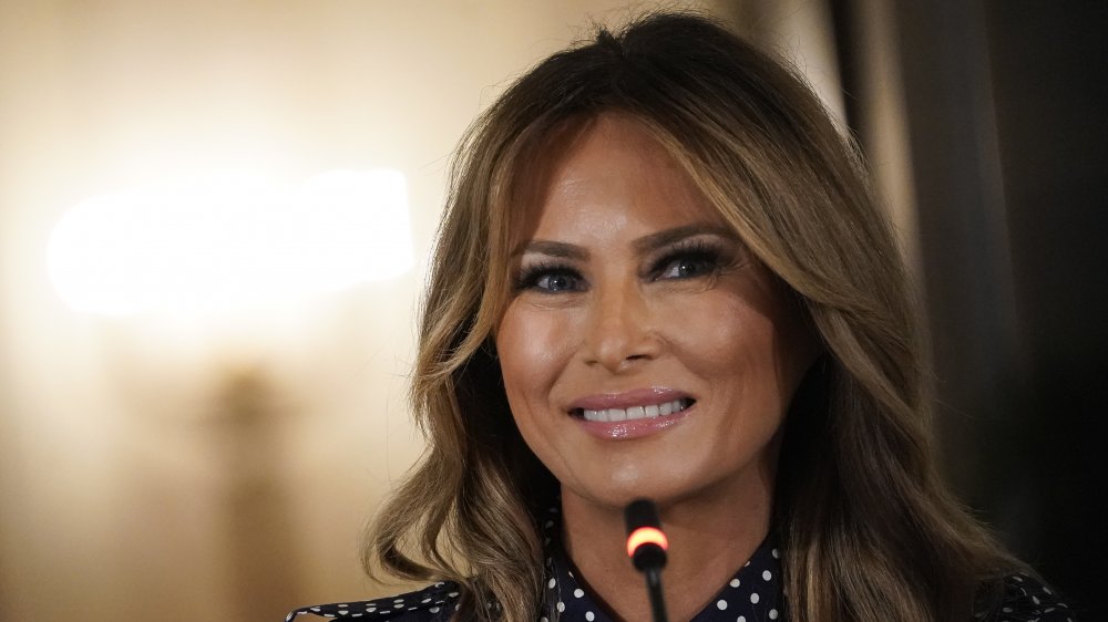 Melania Trump smiling behind a microphone