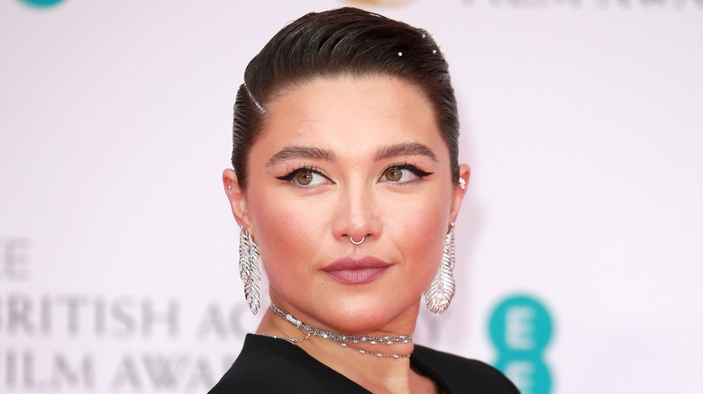 Florence Pugh smirking in silver jewelry