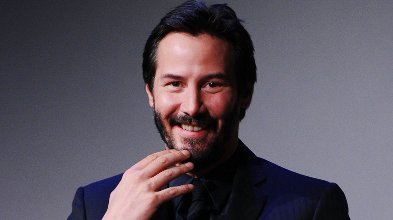 Keanu Reeves holds a hand to his mouth