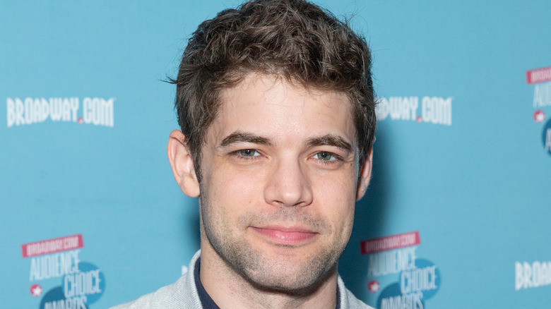 Jeremy Jordan on a red carpet, smiling softly