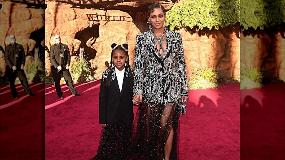 Blue Ivy and Beyoncé in matching outfits, holding hands on the red carpet