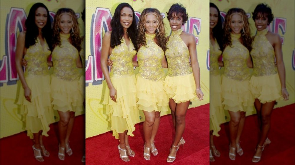 Michelle Williams, Beyoncé, and Kelly Rowland in matching yellow outfits, posing on the red carpet