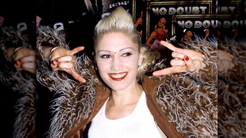 Gwen Stefani smiling while throwing up a rock on sign