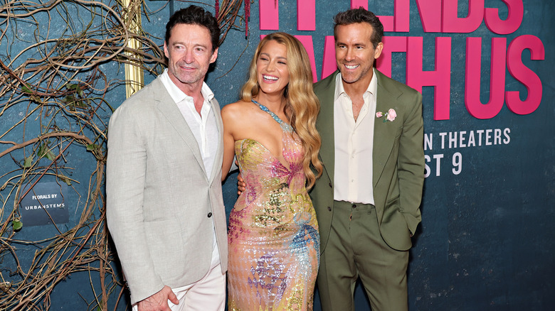 Blake Lively posing between Hugh Jackman, Ryan Reynolds