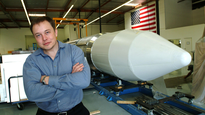 Elon Musk posing with a SpaceX rocke