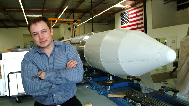 Elon Musk posing with a SpaceX rocke