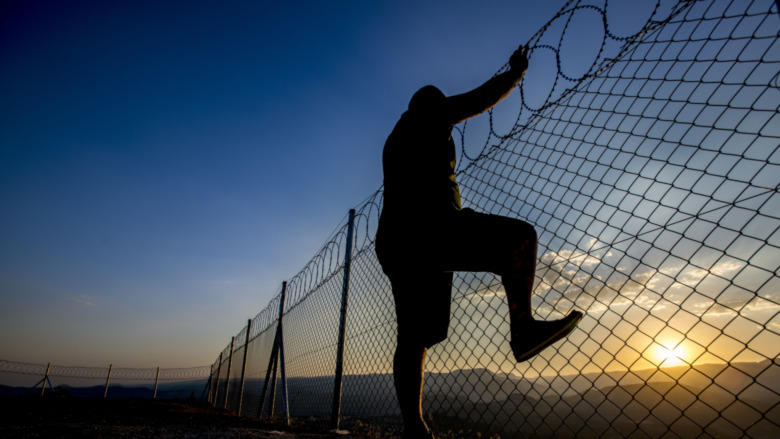 Man trying to escape over fence