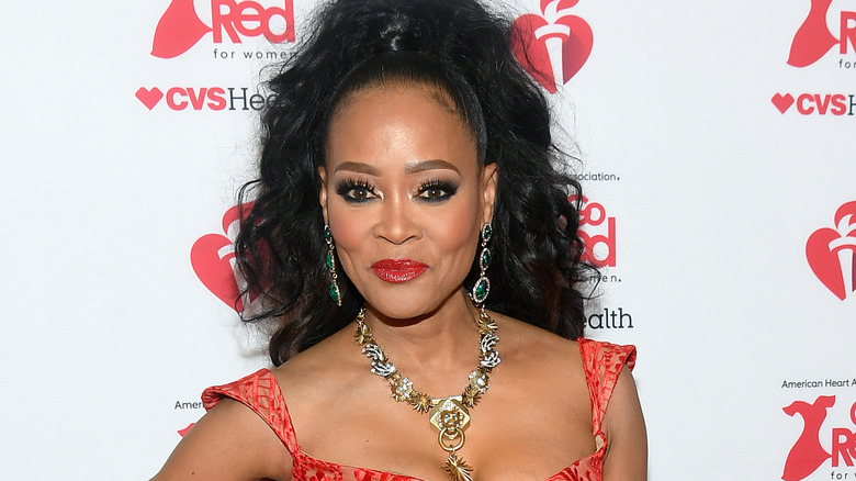 Robin Givens in red dress in front of red for women wall