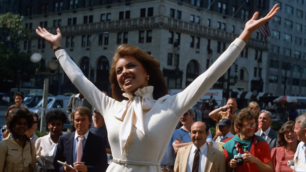 Vanessa Williams raising her arms in the air in front of a crowd 