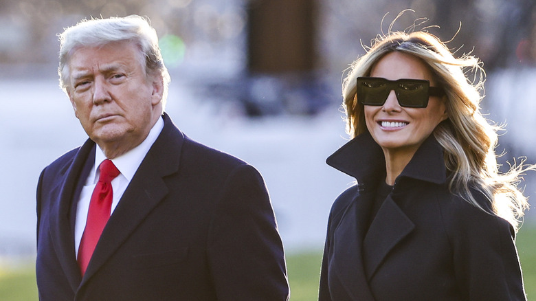 Melania smiles next to Donald Trump