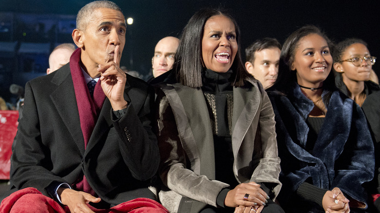 Barack, Michelle, and Sasha Obama sitting in a crowd