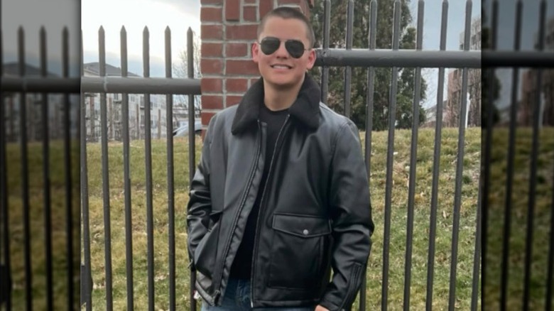 Collin Gosselin wearing a leather jacket while standing near of a fence